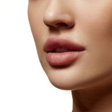 Close-up of a woman's lips and lower face, showcasing smooth skin and full lips, relevant to discussions on filler treatments and aging myths.