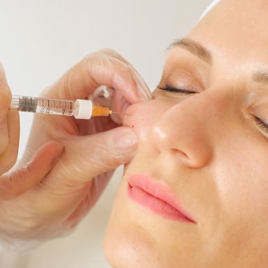 A woman receiving a cheek filler injection as part of a cosmetic treatment.