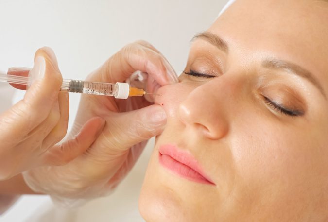 A woman receiving a cheek filler injection as part of a cosmetic treatment.